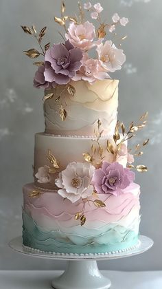 a multi - tiered cake with flowers and leaves on the top is decorated in pastel colors