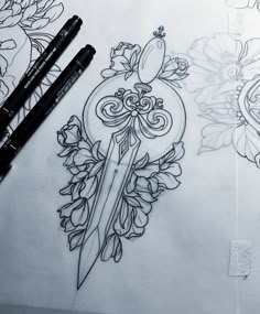 two pencils sitting on top of a piece of paper next to some flowers and a knife