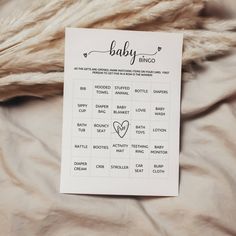 a baby shower game is on top of a bed with fluffy white sheets and fur