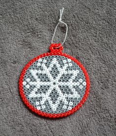 a red and white ornament hanging from a hook on a gray surface with dots