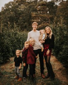 a family poses for a photo in front of a pond with fall foliage and trees