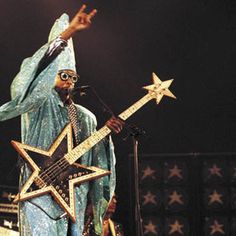 a man dressed in blue and holding a star on top of a guitar while standing next to a microphone