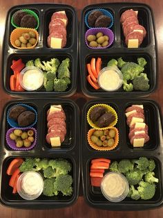 four black trays filled with different types of food on top of a wooden table