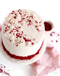 a cake with white frosting and red sprinkles