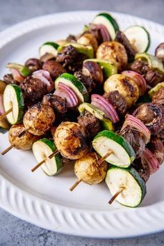 a white plate topped with meat and veggies on skewered in sauce