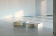 an empty room with white walls and two stools on the floor in front of it