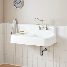 a bathroom sink with a clock on the wall above it and a towel rack in front of it