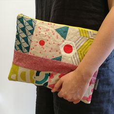 a woman is holding a colorful patchwork clutch bag in her left hand and the other one has a red button on it