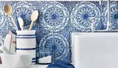 a blue and white tile backsplash with utensils in a vase next to a sink