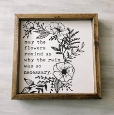 a wooden frame with flowers on it and a quote in the middle that reads, may the flowers remind us why the rain was so necessary