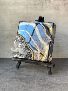 a blue and gold marbled object sitting on top of a wooden stand with ice crystals