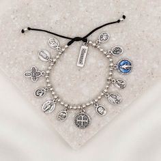 Glory Saints & Angels Bracelet silver tone saint medal charm bracelet on black slip knot cording with blessed charm tag Silver Spiritual Rosary Bracelet For Blessing, Adjustable Spiritual Jewelry With Miraculous Medal, Adjustable Spiritual Bracelets With Miraculous Medal, Spiritual Rosary Bracelet With Miraculous Medal, Anthony Hope, Angel Protection, Blessing Bracelet, Angel Bracelet, The Glory Of God