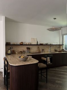 a bowl of fruit is sitting on the counter in this modern style kitchen with wood flooring