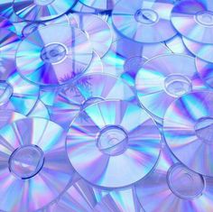 many cd's are stacked on top of each other in blue and purple colors