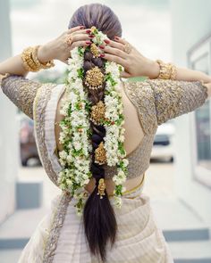 a woman with her hands on her head and flowers in her hair, wearing a white saree