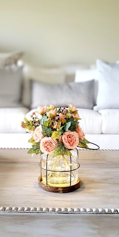 a glass vase filled with flowers sitting on top of a wooden table next to a couch