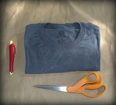 a pair of scissors, t - shirt and pen on a table