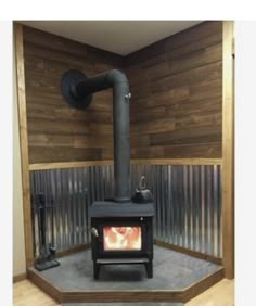 a wood burning stove sitting inside of a wooden room next to a metal wall and pipes