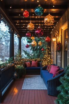 a porch decorated for christmas with lights and ornaments hanging from the ceiling over the couches