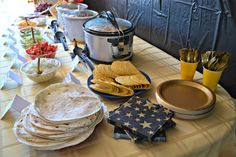 a table topped with plates and bowls filled with food next to crockpots