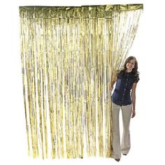 a woman standing next to a curtain with gold foil fringes on it's side