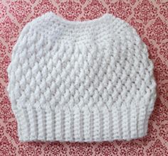 a white knitted hat sitting on top of a red and white patterned tablecloth