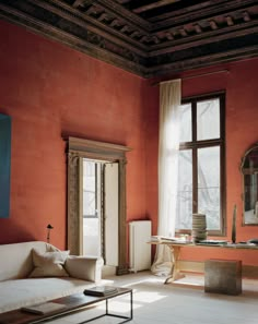 a living room with red walls and white furniture