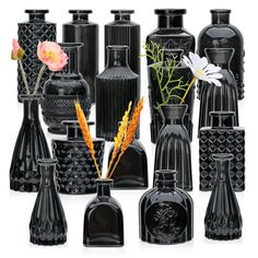 a group of black vases with flowers in them