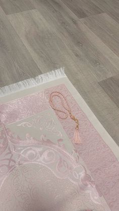 a pink rug on the floor with a tassel hanging from it's end