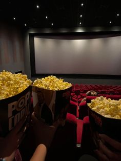 two buckets filled with popcorn sitting in front of a movie screen