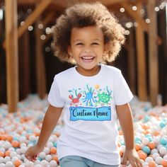 Kids love to wear personalized t-shirts, and this sea life colorful tee will be a favorite!  Boys or girls names in a bold print with a design that looks like an aquarium will make a standout summer t-shirt for your child, or a super birthday gift! * 100% Airlume-combed and ringspun cotton (fiber content may vary for different colors) * Extra light fabric (3.9 oz/yd² (132 g/m²) * Tear-away label - no scratchiness * Machine wash inside out cold (max 30C or 90F); Only non-chlorine bleach; Tumble d Personalized Cotton T-shirt For Playtime, Personalized Fun Short Sleeve T-shirt, Fun Personalized Short Sleeve T-shirt, Customizable Fun T-shirt For Playtime, Customizable Playful Crew Neck T-shirt, Playful Customizable Crew Neck T-shirt, Fun Name Print T-shirt For Playtime, Customizable Fun Blue T-shirt, Girls Names