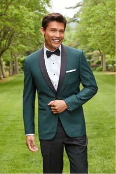 a man in a green tuxedo smiles at the camera