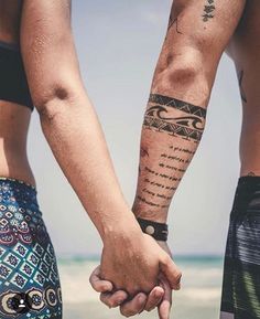 two people holding hands with tattoos on their arms