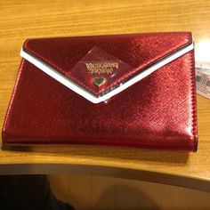 a harry potter red wallet sitting on top of a wooden table next to a pair of scissors