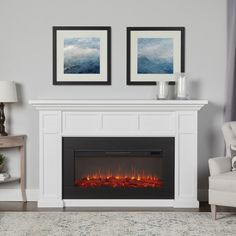 a white fireplace with two framed pictures above it