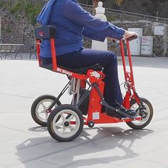 a woman in blue jacket riding on a red motorized scooter with black wheels