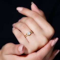 a woman's hand holding an engagement ring with a diamond on it and two fingers