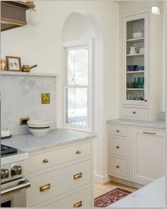 a kitchen with white cabinets and marble counter tops