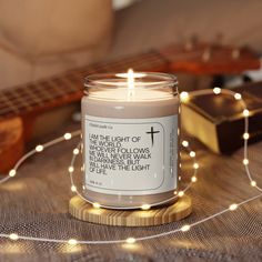 a candle that is sitting on a table with some string lights and a guitar in the background