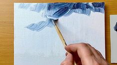 a person is holding a paintbrush in their hand and painting an image on the canvas