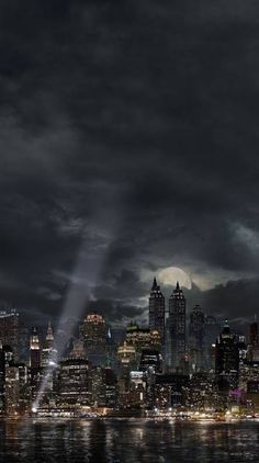 an image of a city at night with lights in the sky and dark clouds above