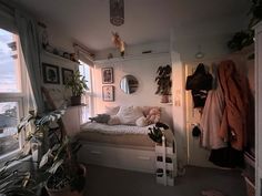 a bedroom with a bed, plants and pictures on the wall