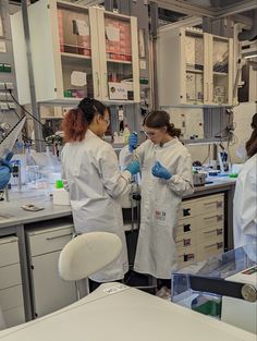 two women in white lab coats working with beaks