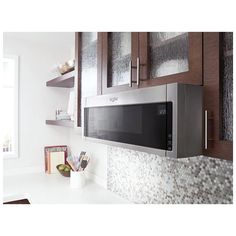 a microwave oven sitting on top of a kitchen counter next to wooden cabinets and drawers