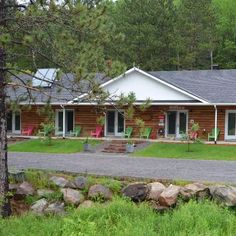 a log cabin sits in the middle of a field with rocks and trees around it