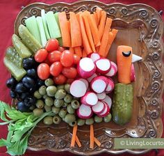 a platter with carrots, radishes, cucumbers and other vegetables