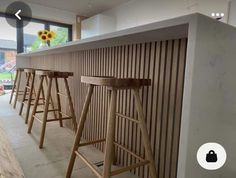 a row of wooden stools in front of a bar with sunflowers on the window sill