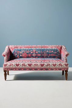 an ornately decorated couch against a blue wall