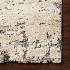 a white rug with black and grey designs on it, sitting on a wooden floor