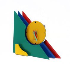 a clock made out of different colored shapes and sizes on a white surface with a yellow top